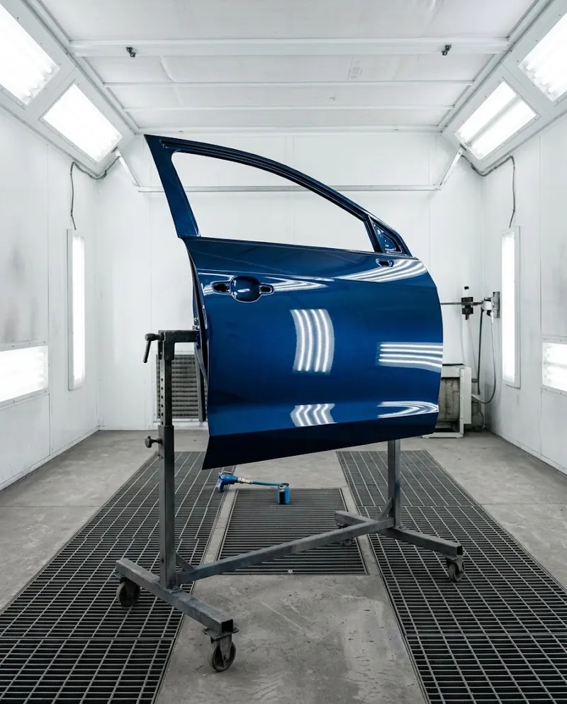 Uma porta de carro acabada de pintar a secar sob as luzes da estufa